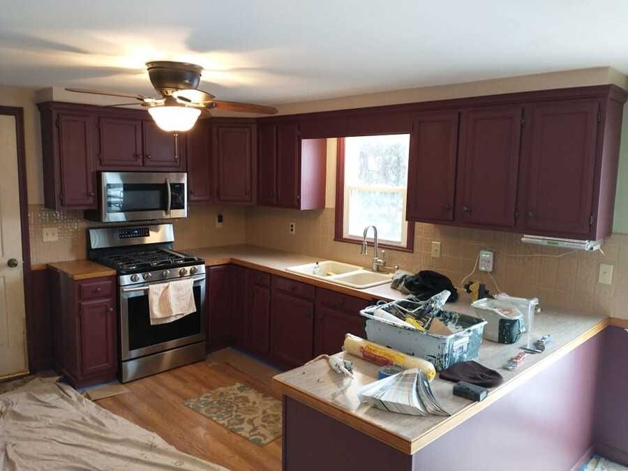 Kitchen cabinets before repainting with tools and drop cloths on the counters