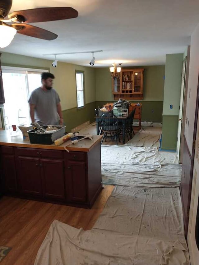 Interior painting in progress with drop cloths, supplies, and room surfaces prepared